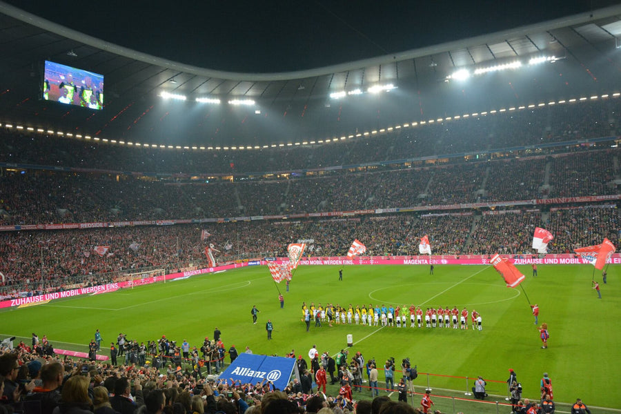 View from the lower tier along the sideline of the Allianz Arena, full stadium under floodlights