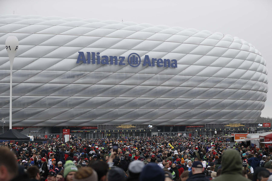 Weiße Fassade der Allianz Arena bei Tag, NFL-Fans vor dem Stadion beim Munich Game 2022